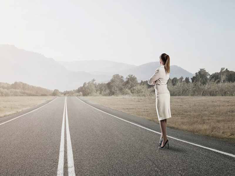 Cross border Third Party Investigations - Woman standing on the side of a long straight road