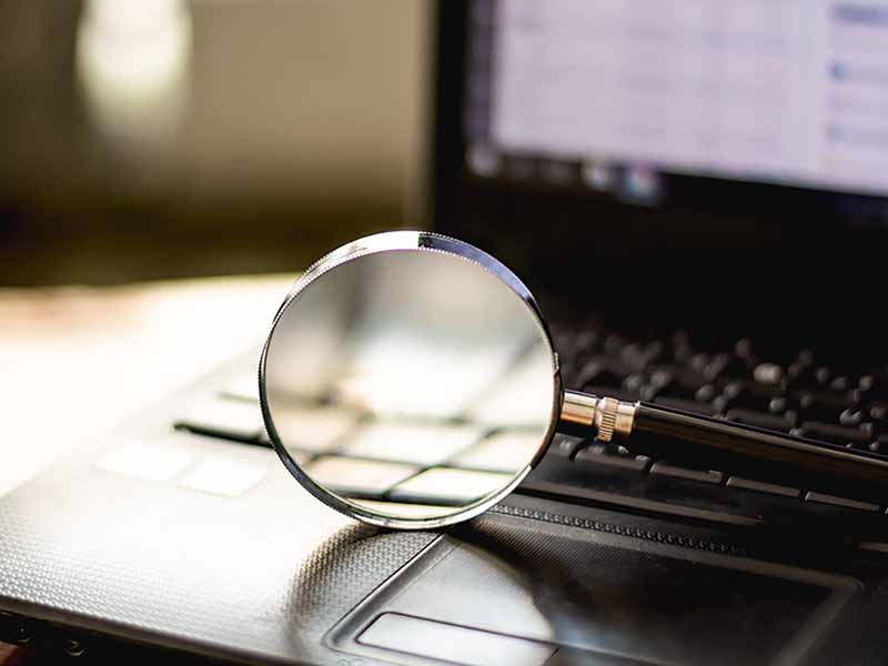 Standard and Custom Background Checks - Magnifying glass in front of computer