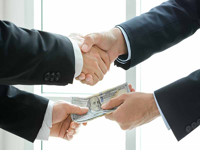 Where the Bribes Are - two men shaking hands while exchanging money